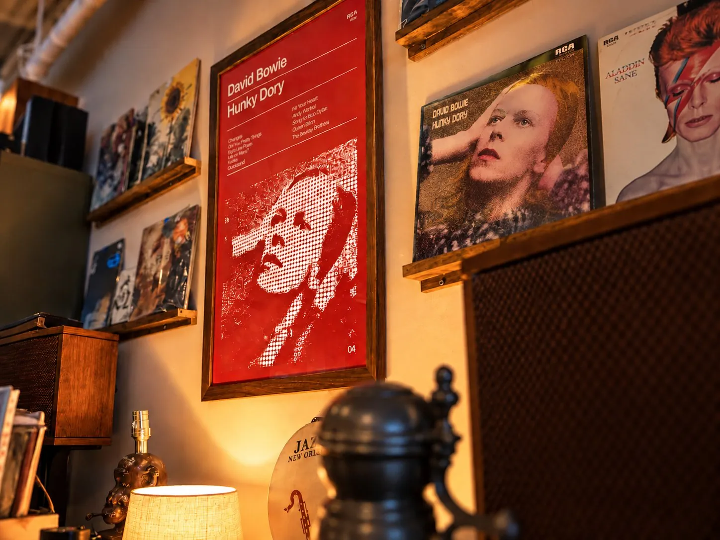 A framed red David Bowie Hunky Dory poster on a wall of records, next to the original album cover