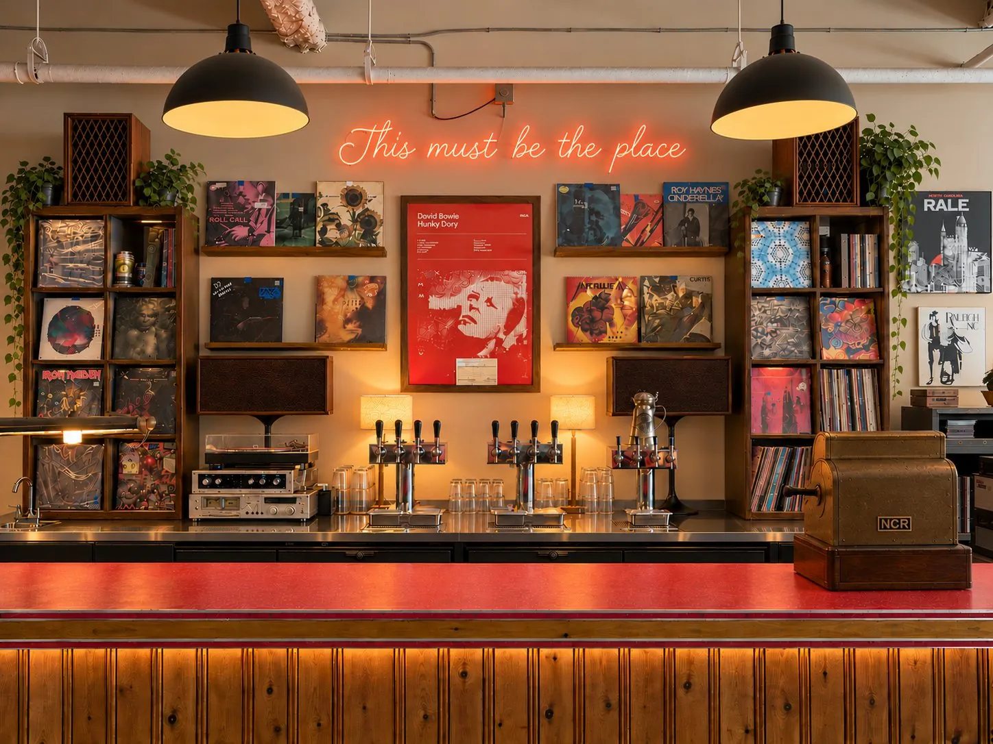 The bar at Hunky Dory: taps under a neon sign reading This must be the place, framed by record shelves and a red David Bowie Hunky Dory poster