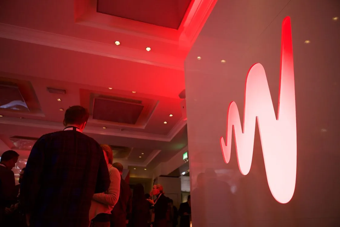 A glowing red W on a white wall at an Insights reception
