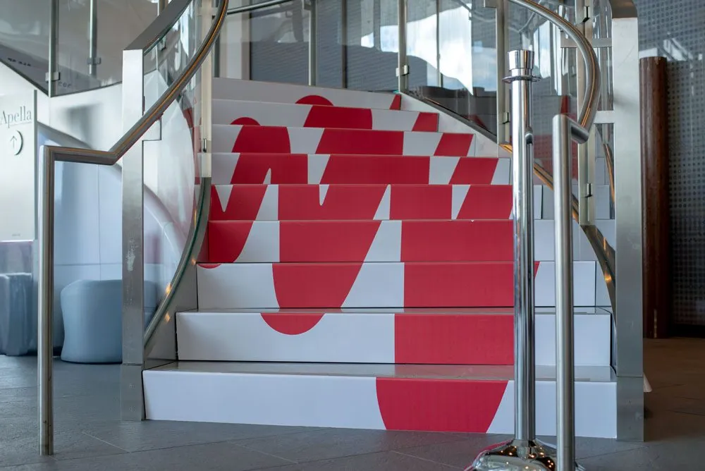 A curved staircase with the red JW Player W wrapped across every step