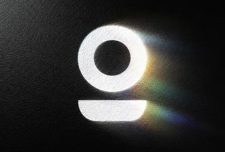 Overflo logomark, a white ring over a rounded bar, on black textured paper with a prism of light