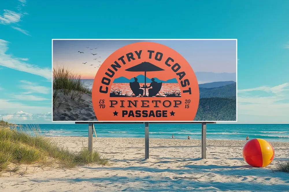 A Country to Coast Pinetop Passage billboard on a beach: two people under an umbrella, mountains behind