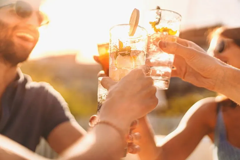 Friends raising glasses of cocktails in a toast at golden hour