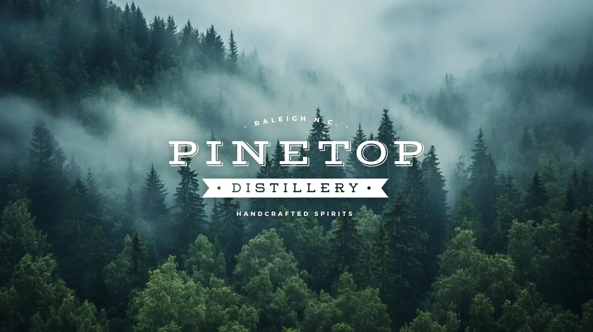 The Pinetop Distillery logo in white over mist rolling through a dense pine forest on a mountainside