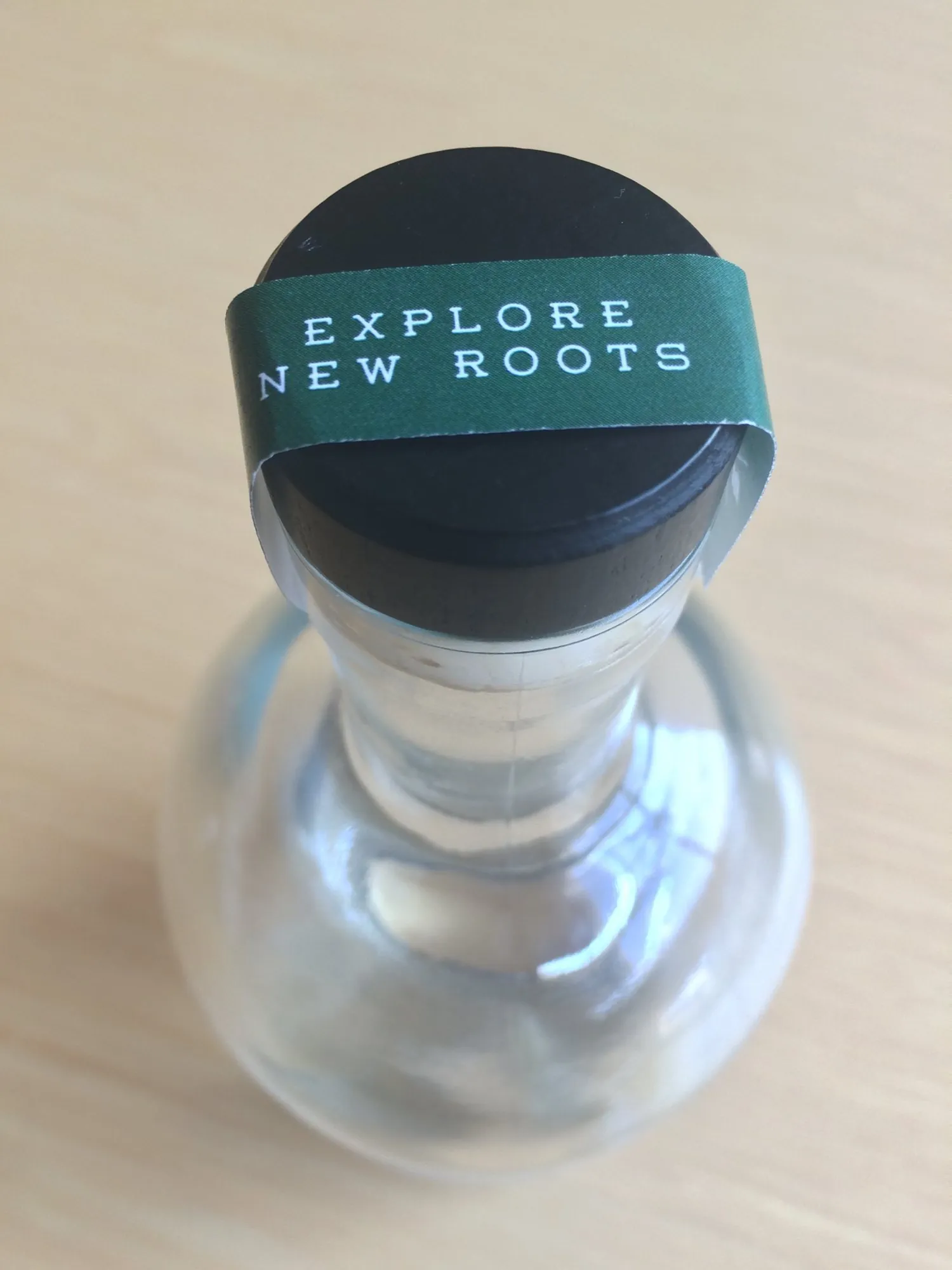 A green neck strip over a black cap reading Explore New Roots