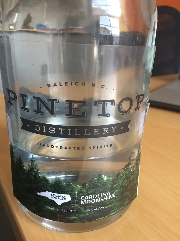 A reference bottle wrapped in a hand-printed clear Pinetop label, Carolina Moonshine, 80 proof
