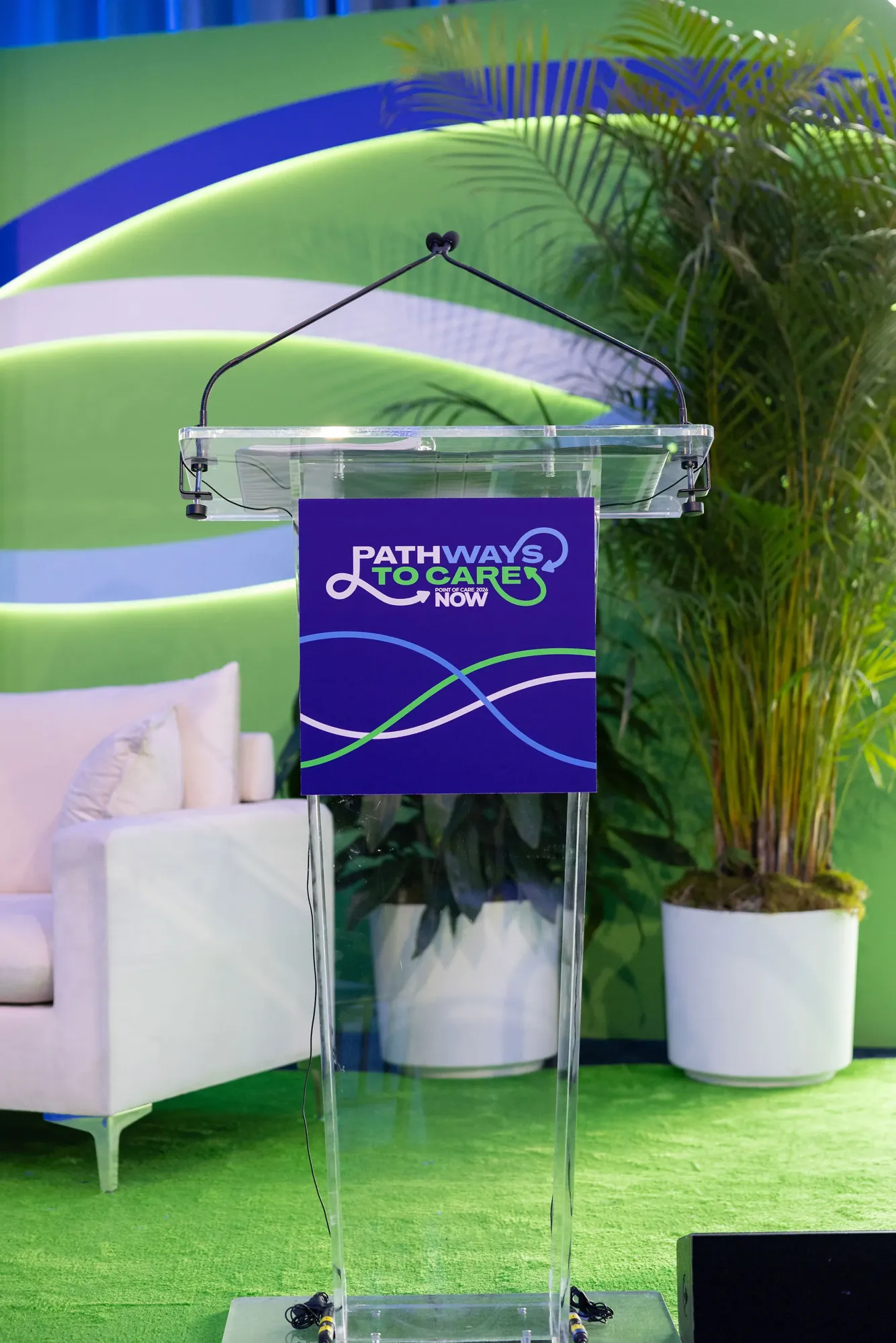 The acrylic podium with a purple Pathways to Care sign, three crossing lines in blue, green and white below the logo